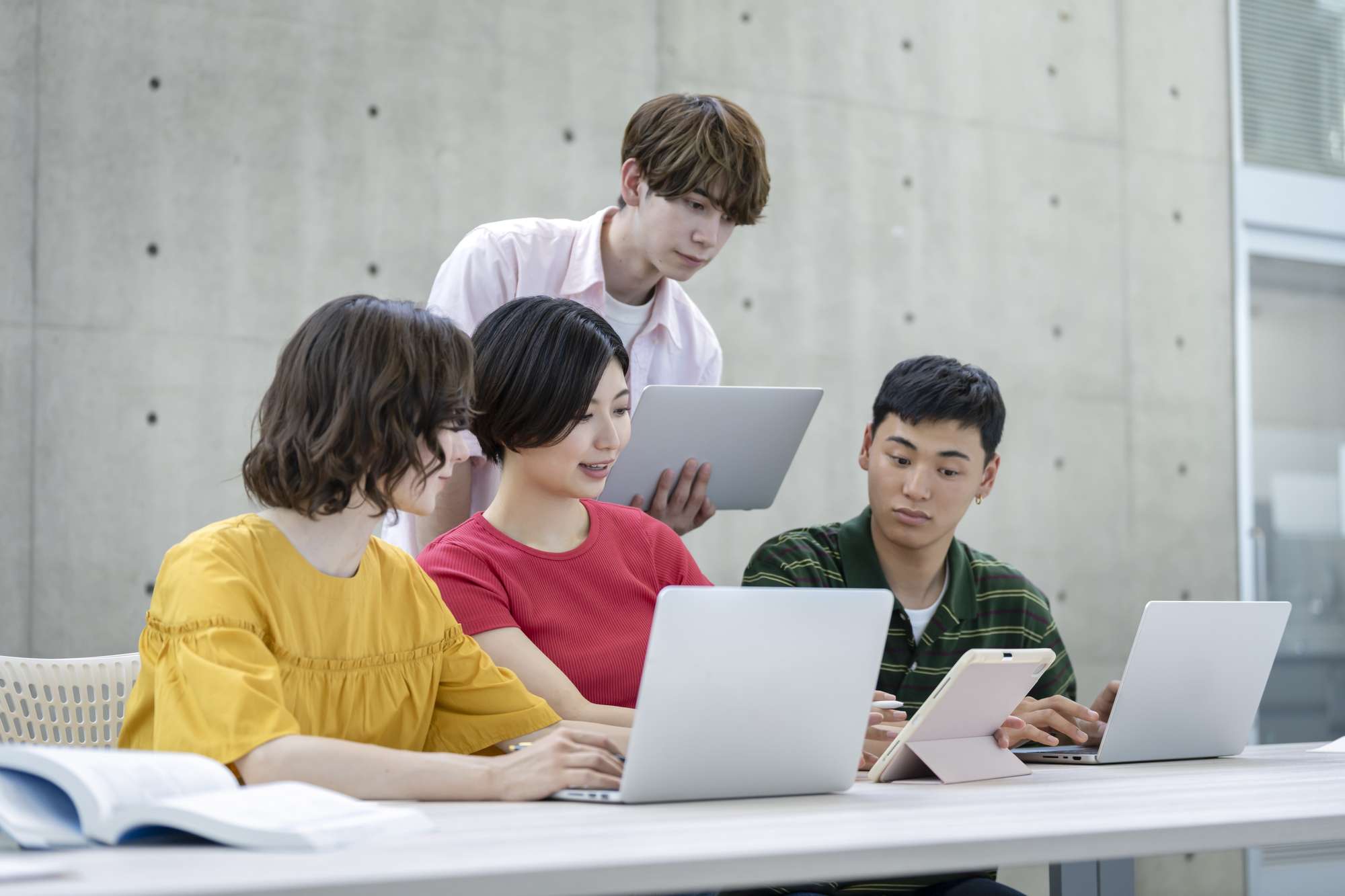 パソコンを見ながらディスカッションする大学生