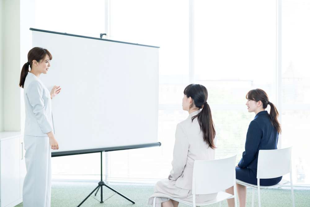 スクリーンを前に説明する女性