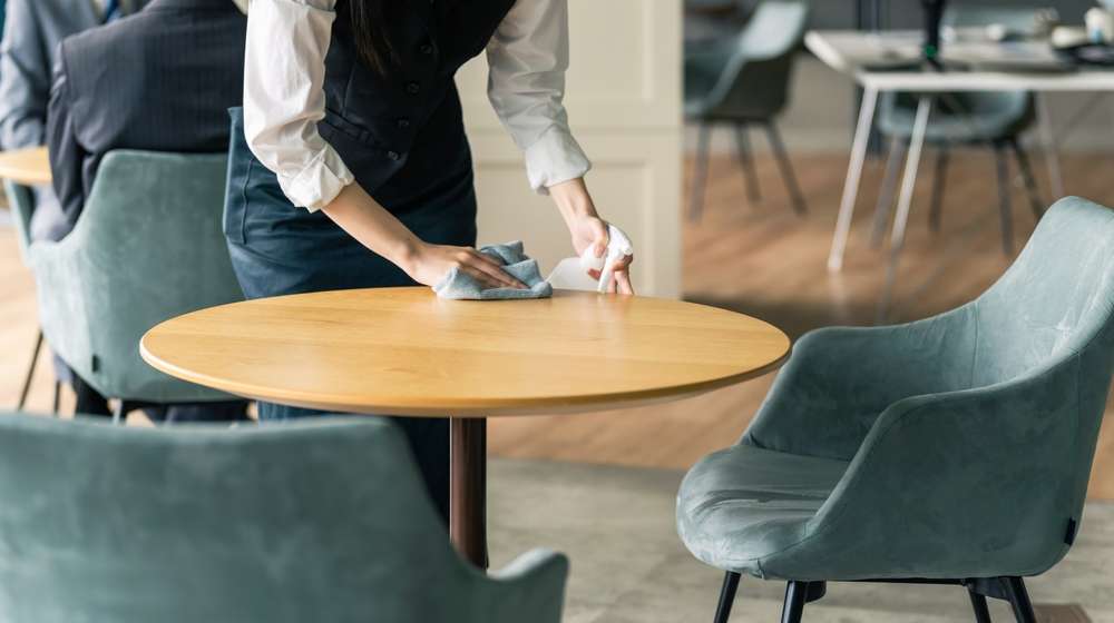 飲食店のテーブルを拭く従業員