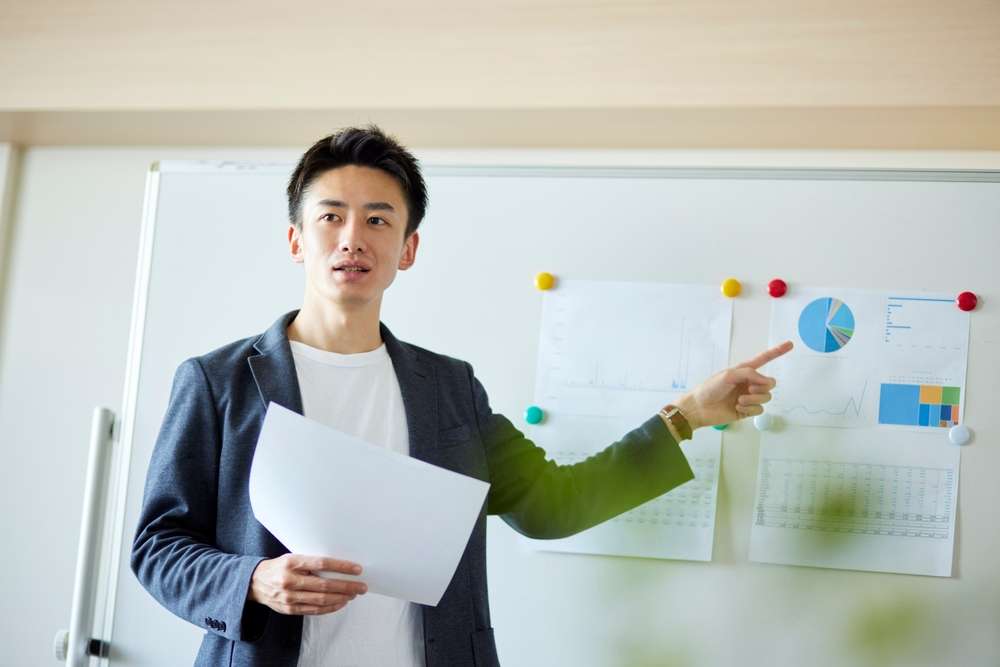 ホワイトボードの前でプレゼンをする人