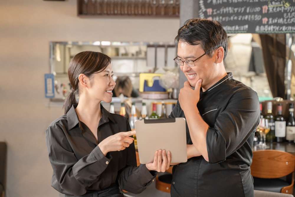 タブレットを見て話し合う飲食店スタッフ