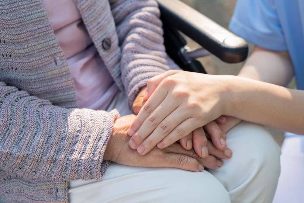 高齢の女性の手を取る介護士