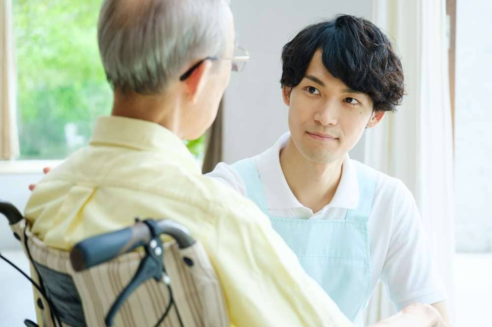 車いすの男性に語りかける介護士
