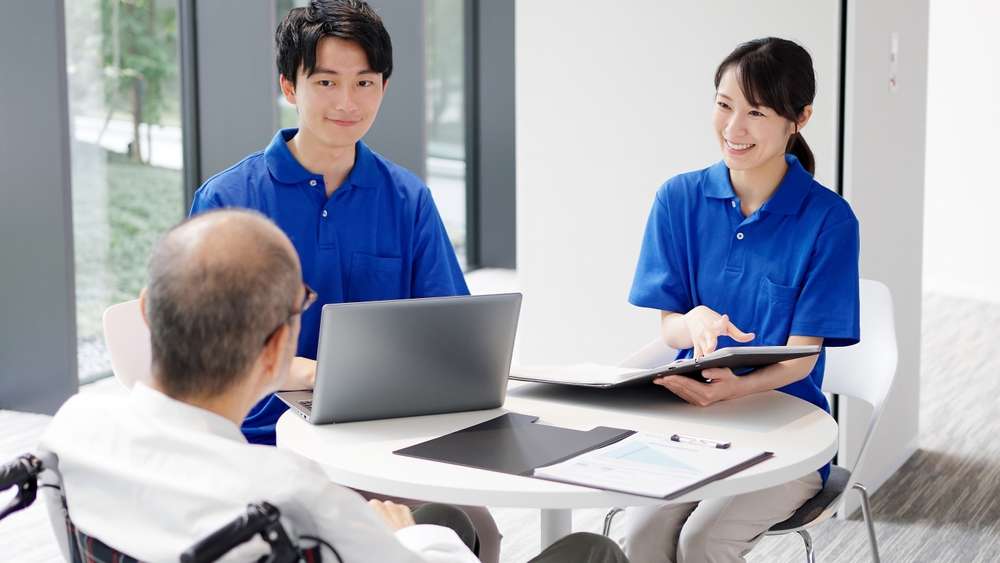 車いすの男性と話し合う男女