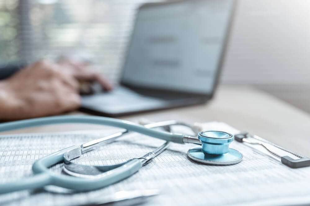 机に置かれたノートパソコンと聴診器